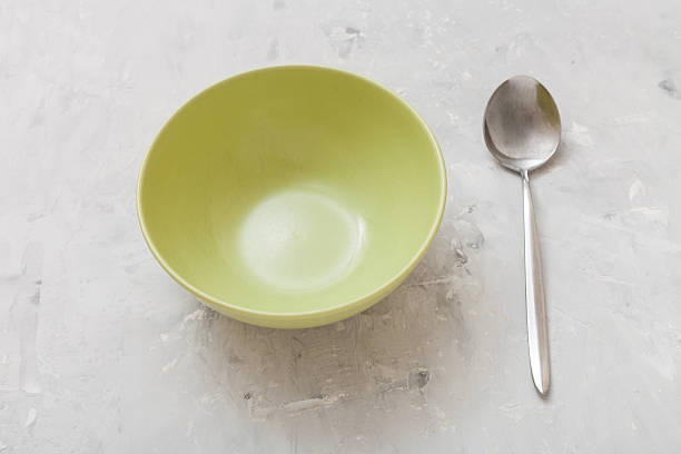 green bowl and steel spoon on gray concrete plate
