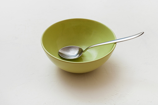 green bowl with spoon on white plastering plate