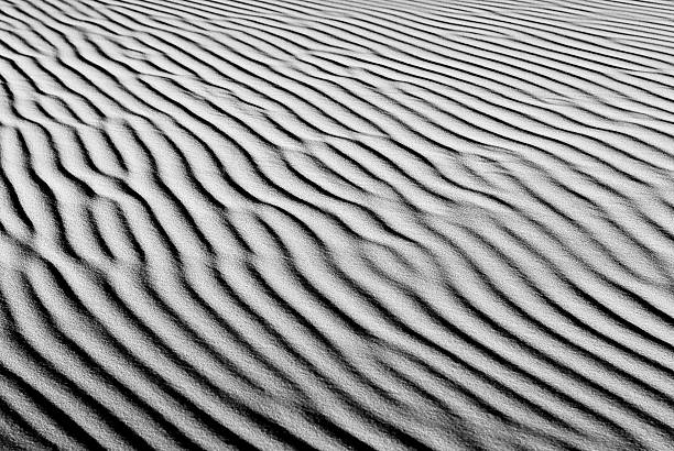Desert sand waves background Black and white desert sand waves background. Focal at 50mm. high contrast stock pictures, royalty-free photos & images