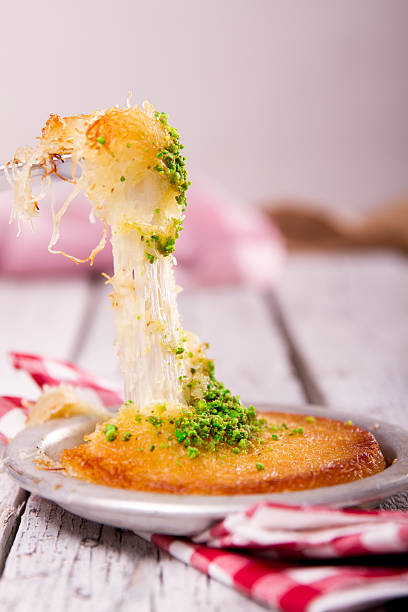 Turkish dessert kunefe with pistachio powder on wood background stock photo