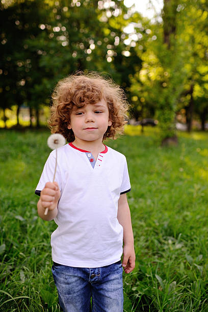 istock baby boy with dandelion in hand on green background 617580250