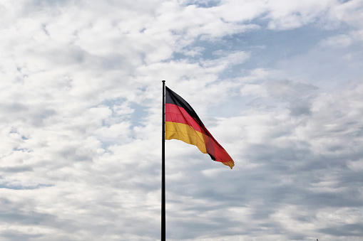 German flag waves with cloudy sky background