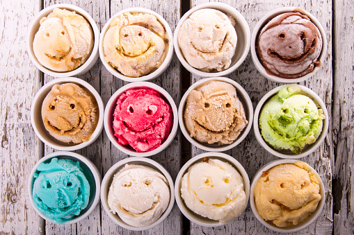 Selection of gourmet flavours of Italian ice cream in vibrant colors served on an old rustic wooden table in an ice cream parlor, overhead view