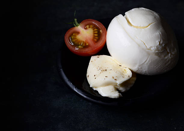 istock Delicious cheese mozzarella, tomatoes and basil leaves in black bowl 617582244