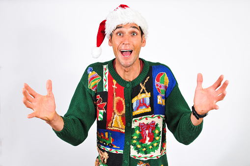 A young man in an ugly sweater is excited about Christmas. Studio shot with copy space.
