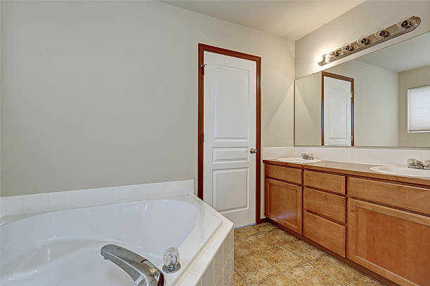 istock White bathroom interior with corner bathtub and vanity cabinet. 617583008