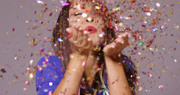 istock Cute young woman blowing confetti 617583776