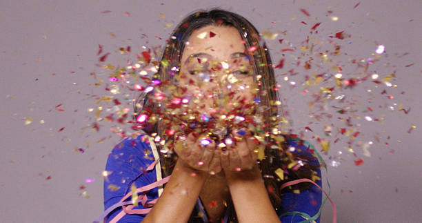 istock Cute young woman blowing confetti 617583806