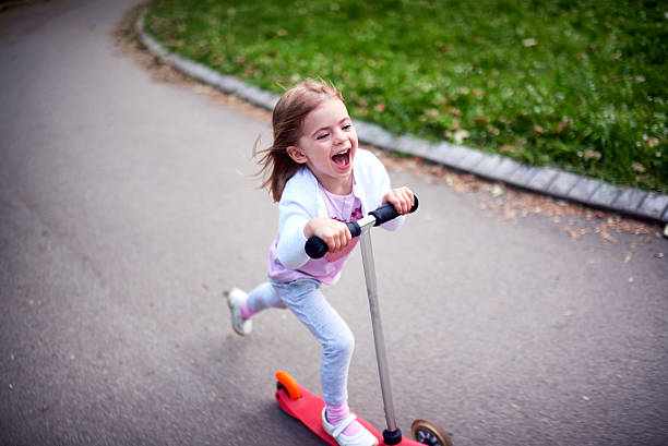 Girl riding push scooter Cute toddler girl riding push scooter in city park push scooter stock pictures, royalty-free photos & images