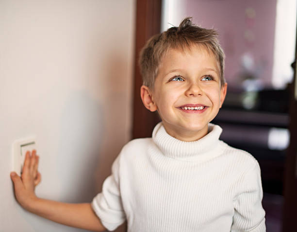 Little boy turning on light Happy little boy playing with light switch. light switch photos stock pictures, royalty-free photos & images