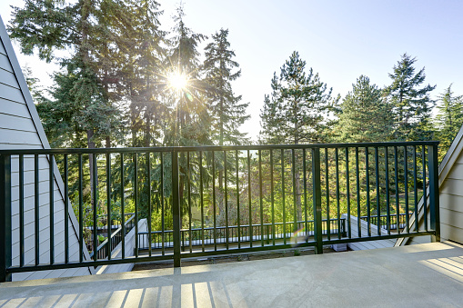 Apartment building in residential area. View from empty balcony with scenic view, sun shining through fir trees. Northwest, USA