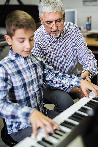 istock Man giving lesson piano to boy 617586822
