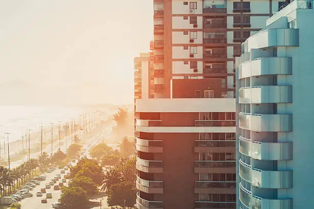 Street of Rio de Janeiro near beach and ocean in luxury Barra district with buildings and cars, on a hot sunny summer day, sunset or dawn, view from top, vintage colour filter