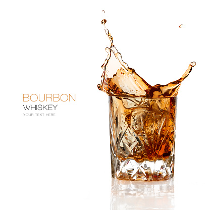 Bourbon whiskey splash in an elegant glass cut glass isolated on white background with copy space for text