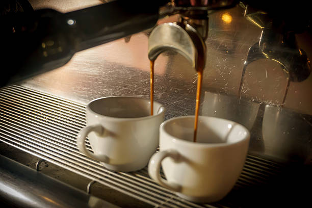 istock Coffee maker pouring hot coffee in two cups 617591426