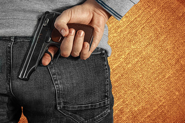 istock Man holding a gun in his hand behind his back 617594712