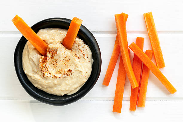 Hummus with Carrot Sticks Top View Hummus with carrot sticks.  Top view over white timber. carrot stock pictures, royalty-free photos & images