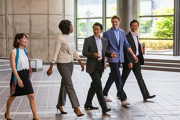 mixed race group of business people walking through japanese office - respect japan business togetherness imagens e fotografias de stock