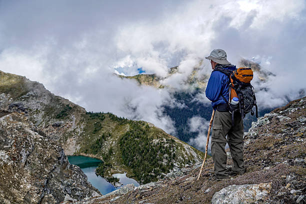 istock Hiker on Mountaintop Overlooking Clouds and Lake 617597554