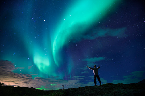 Person standing on hill watching aurora borealis in  iceland Badlands