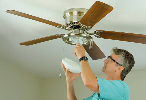 Professional or DIY home owner doing ceiling fan repair work stock photo