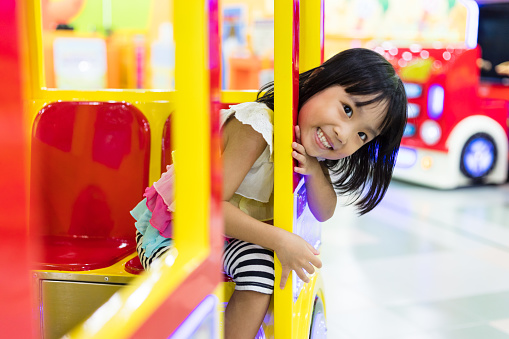Asian Chinese Little Girl Riding Toy Bus at indoor playground.