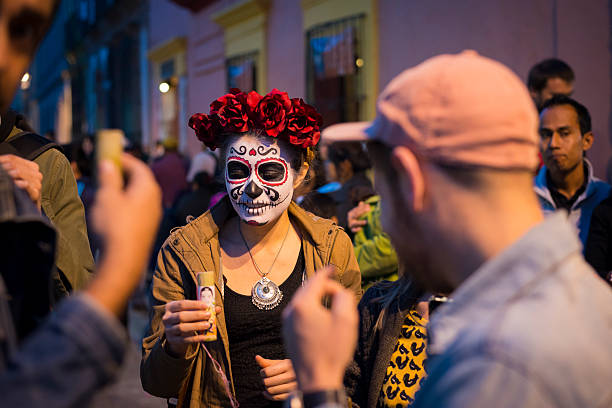 Celebrating Day of the Dead in Oaxaca, Mexico Oaxaca, Mexico - November 1, 2014: A young woman holds an alcoholic drink, probably mezcal, while part of a crowd celebrating Day of the Dead ("Día de los Muertos" in Spanish) in Oaxaca, Mexico. peyote cactus stock pictures, royalty-free photos & images