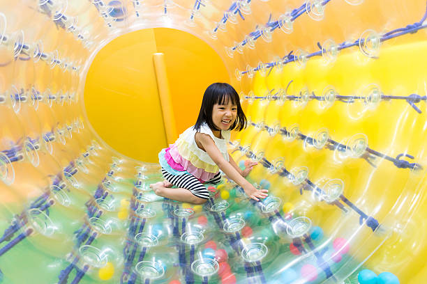 happy asian chinese little girl playing roller wheel - inflatable child playground leisure games imagens e fotografias de stock