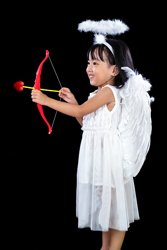 Happy Asian Chinese Little Angel WIth Bow And Arrow in isolated dark black studio background.