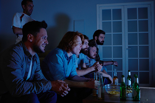 Group of worried fans watching tv at night