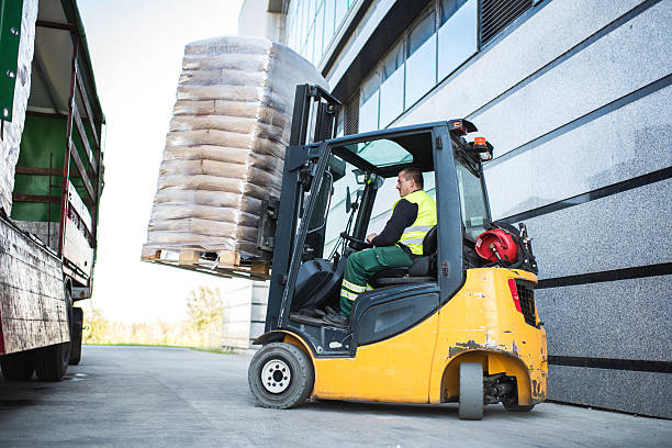 worker loading pallet with a forklift into a truck. - empilhadora imagens e fotografias de stock