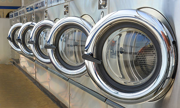 Laundry shop Row of industrial laundry machines in laundromat. laundry stock pictures, royalty-free photos & images