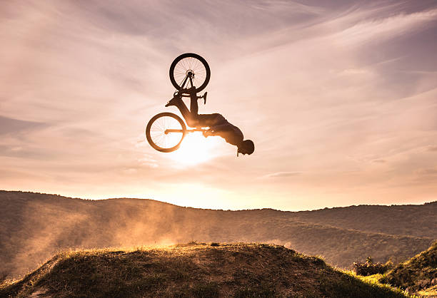 Skillful cyclist doing backflip against the sky at sunset. Mountain bike rider exercising at sunset and performing backflip against the sky. Copy space. mountain bike photos stock pictures, royalty-free photos & images