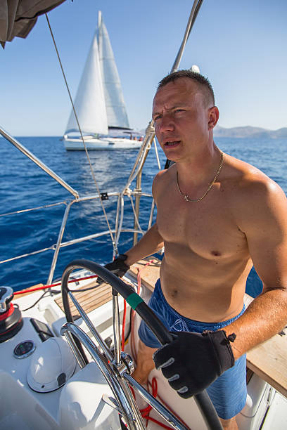 istock Young man steers sailing yacht boat during the regatta. 617736634