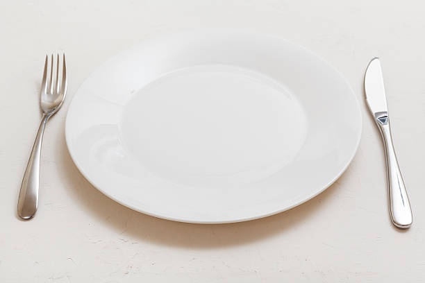 istock white plate with knife, spoon on white plaster 617738824