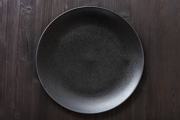 top view of black plate on dark brown table stock photo