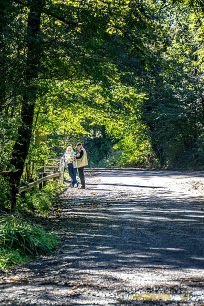 pareja mirando el mapa en el camino del bosque - map uk hiking reading fotografías e imágenes de stock