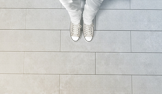 Person taking photo of his feet stand on concrete floor, isolated, top view, clipping path. Ground design mock up. Man wear gumshoes and watching down. Deck flooring mockup template.
