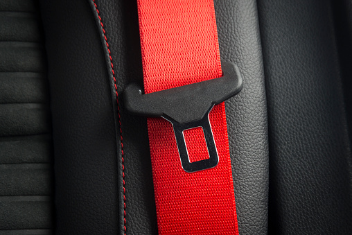 Red seat belt fastener  lock in black leather interior