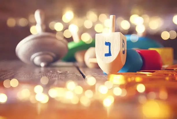 Image of jewish holiday Hanukkah with wooden dreidels colection (spinning top) and chocolate coins on the table. Glitter overlay