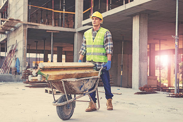 Construction worker in reflective clothing pushing wheelbarrow