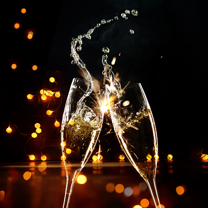 Champagne pouring into a tall glass on the background of bokeh. A popular alcoholic drink.