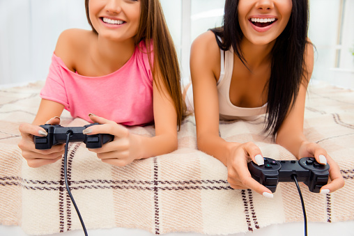 Close up photo of cheerful smiling women playing on joysticks