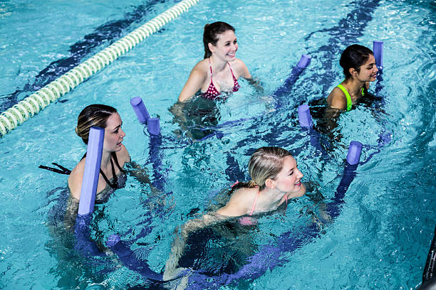 istock Happy fitness class doing aqua aerobics with foam rollers 617751782