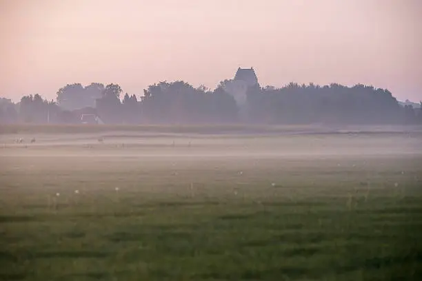 Old rural dutch village with churchtower in mist. Geesteren. Gelderland. The Netherlands.