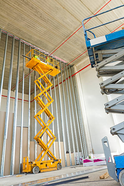 plataforma elevadora de tijera en un sitio de construcción. - wall plasterboard vehicle interior indoors fotografías e imágenes de stock
