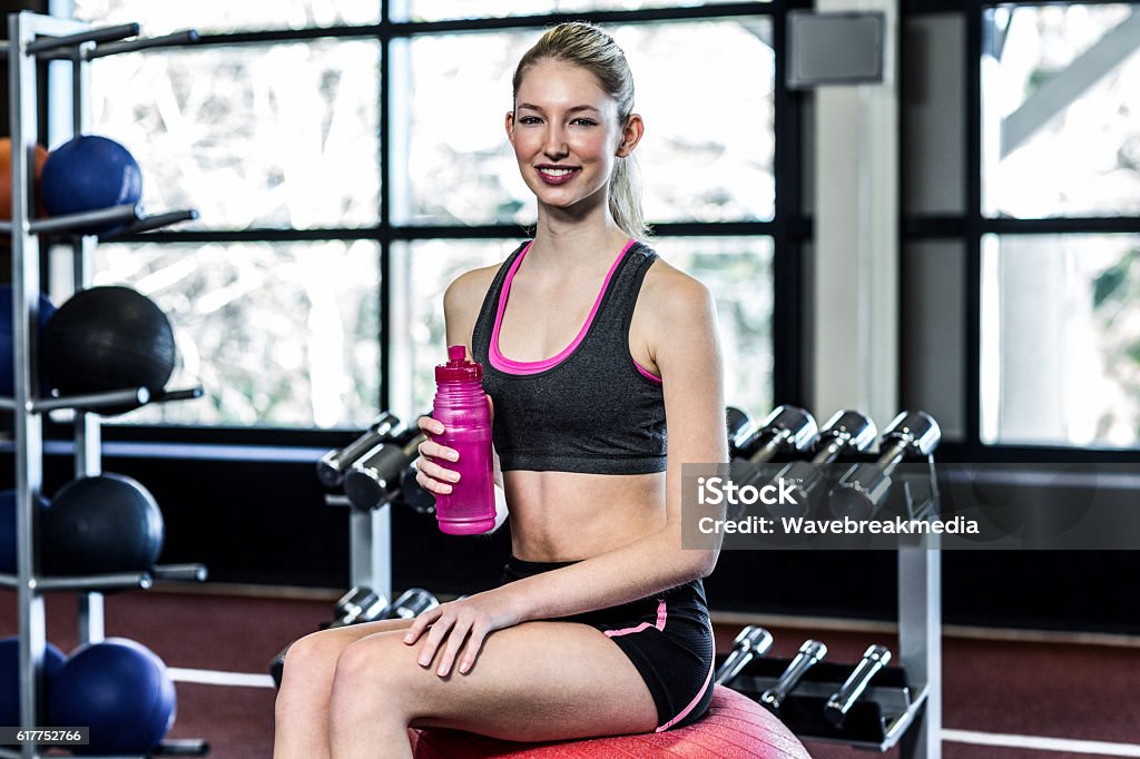 Smiling fit woman sitting on exercise ball Smiling fit woman sitting on exercise ball at the gym Activity Stock Photo