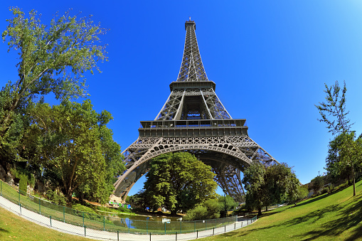 Huge and beautiful Eiffel Tower. The picture was taken Fisheye lens. At the foot of the tower is designed park with paths and pond