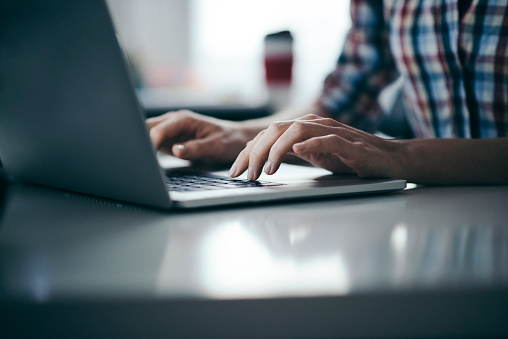 Close up on female hands typing on laptop at office desk