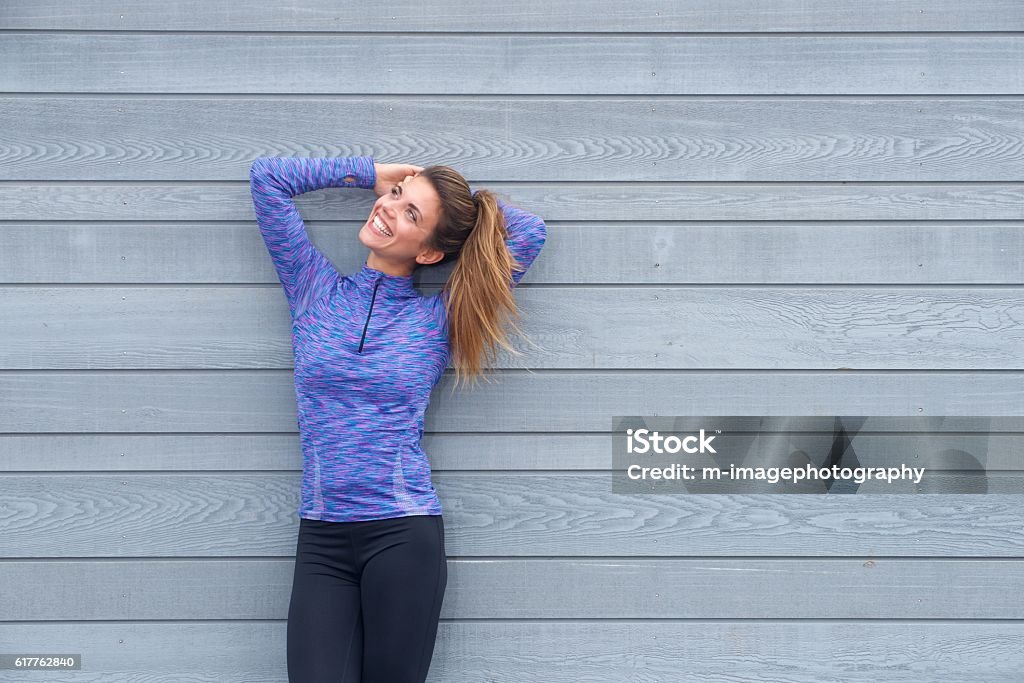 Laughing woman standing with hands behind head Portrait of laughing woman standing with hands behind head Running Stock Photo